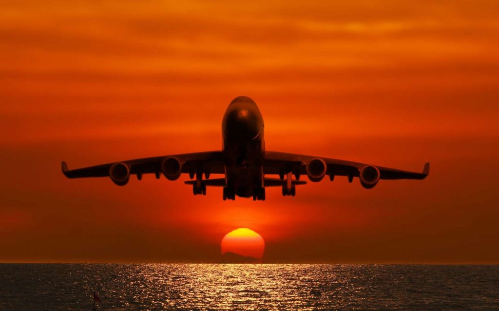Passagiersvliegtuig boven de zee bij zonsondergang