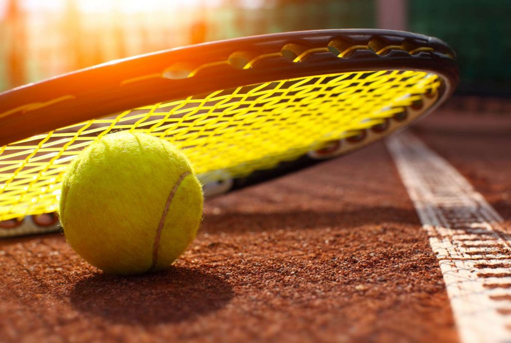 Tennisbal op een tennisbaan met zonlicht