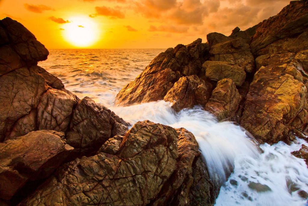 Zee met rotsen bij zonsondergang